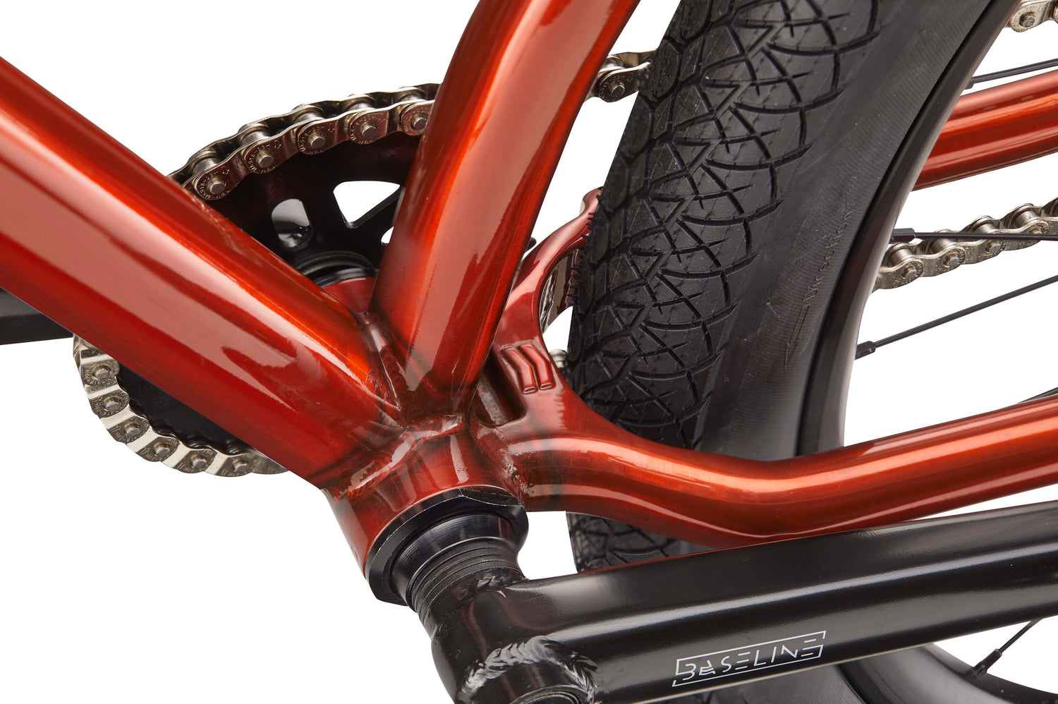 Close-up of a red HARO Steel Reserve TS frame showing the chain, rear tire, crank arm, and part of the gear mechanism.